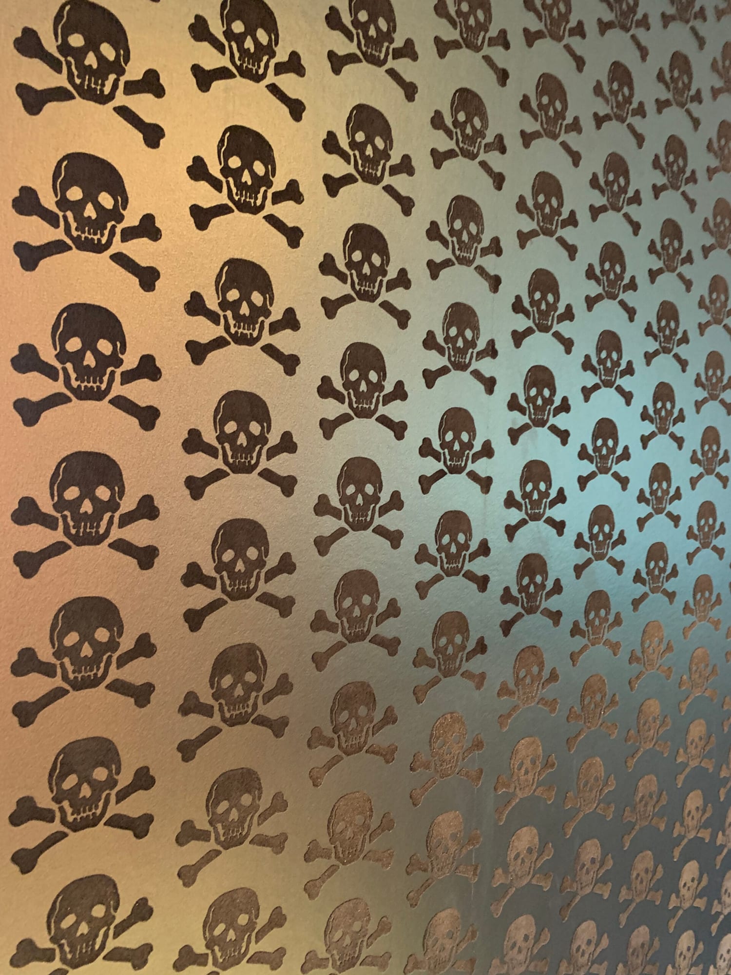 Photo of a loft games room decorated with metallic gold skull-and-crossbones patterned wallpaper and a brown leather sofa.